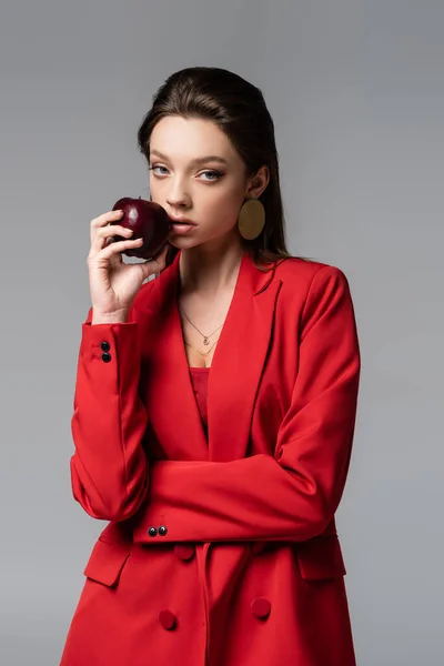 Νεαρή Γυναίκα Κόκκινο Κοστούμι Που Κρατά Μήλο Απομονωμένο Γκρι — Φωτογραφία Αρχείου