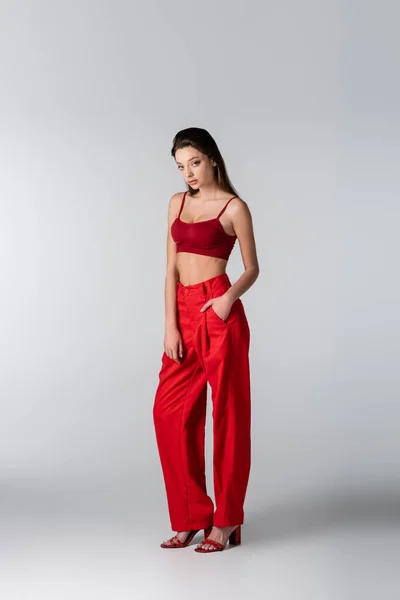 Pełna Długość Młodej Kobiety Czerwonej Bluzce Spodniach Pozujących Ręką Kieszeni — Zdjęcie stockowe