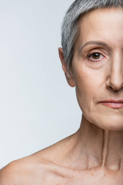 обрезанный вид женщины средних лет, смотрящей на камеру, изолированную на сером