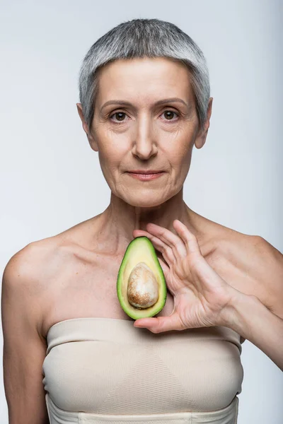 Жінка Середнього Віку Тримає Половину Зеленого Стиглого Авокадо Ізольовано Сірому — стокове фото