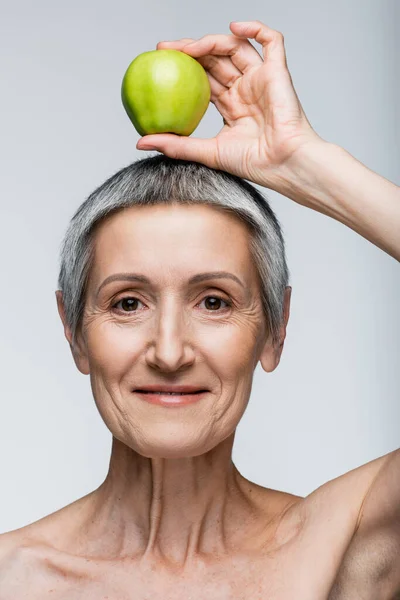 Kafasının Üstünde Yeşil Elma Tutan Neşeli Orta Yaşlı Kadın Gri — Stok fotoğraf