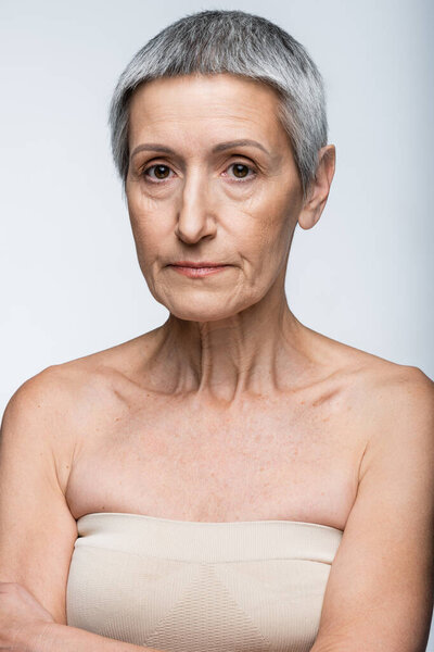 mature woman with bare shoulders isolated on gray