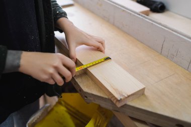 Cropped view of furniture designer measuring wooden board in workshop  clipart