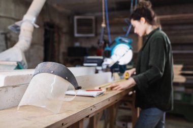Atölyede çalışan bulanık marangozun yanındaki güvenlik vizörü. 