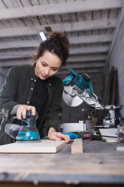 Marangoz atölyede ahşap döşeme talaşı parlatıyor. 