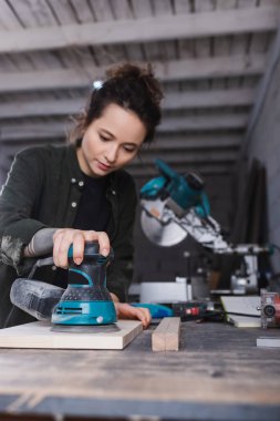 Sander, atölyede tahta cilalayan bulanık marangozun elinde. 