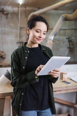 Atölyede koruyucu vizör yanında dijital tablet kullanan pozitif mobilya tasarımcısı 