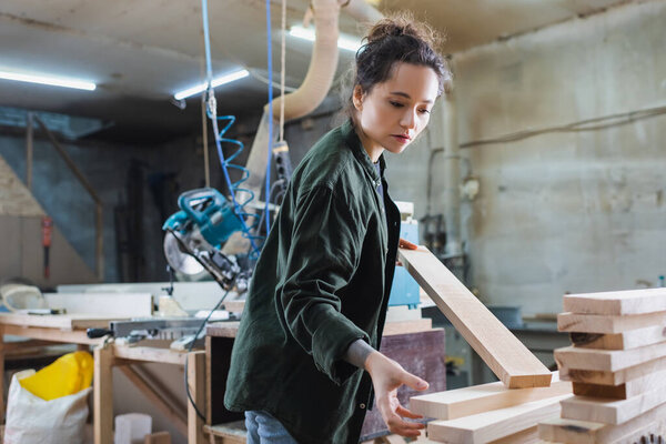 furniture designer holding wooden planks in workshop 