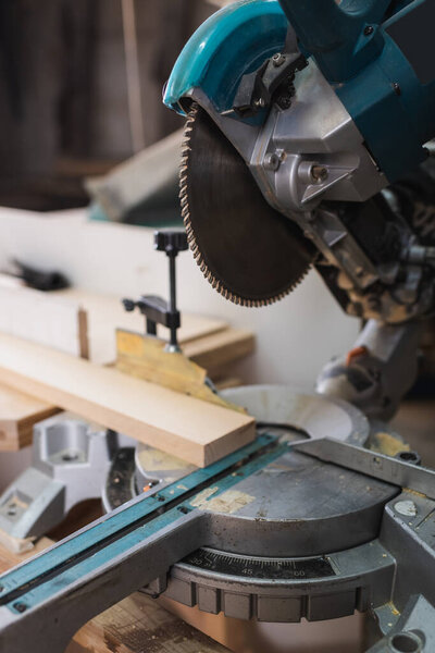 Close up view of miter saw and wooden board in workshop 