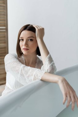 Cüppeli esmer kadın küvetin yanında poz veriyor. 