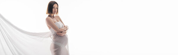 Беременная женщина в полотне смотрит на камеру, изолированную на сером, баннер 