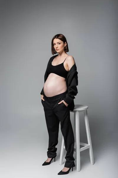 Volledige Lengte Van Zwangere Vrouw Hakken Pak Poseren Buurt Stoel — Stockfoto