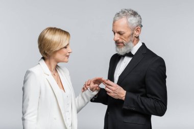 Gelinin parmağına yüzük takan yetişkin damat gri üzerine izole edilmiş. 
