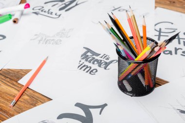 Ahşap masadaki çeşitli yazı tipleriyle bulanık kağıtların yanında renkli kalemler