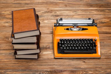 high angle view of stacked books and typewriter on wooden desk clipart