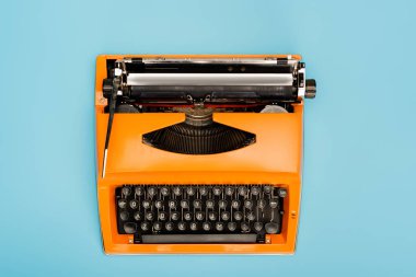 top view of orange typewriter with black keyboard isolated on blue clipart