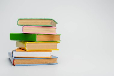 stacked books with multicolored covers on grey background clipart