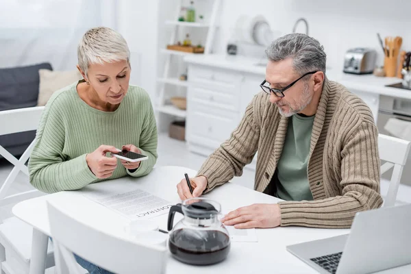 Pensioner Writing Document Wife Taking Photo Contract Kitchen — Stock Photo, Image