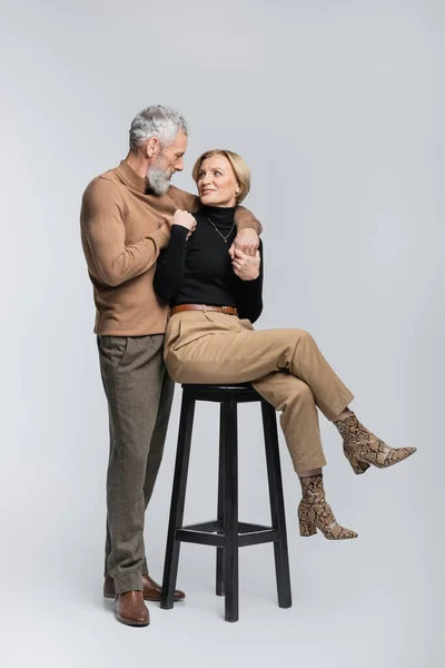 Mature Man Hugging Stylish Wife Sitting Chair Grey Background — Stock Photo, Image