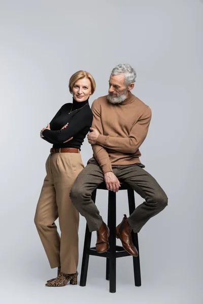 Full Length Stylish Woman Crossing Arms Mature Husband Sitting Chair — Stock Photo, Image