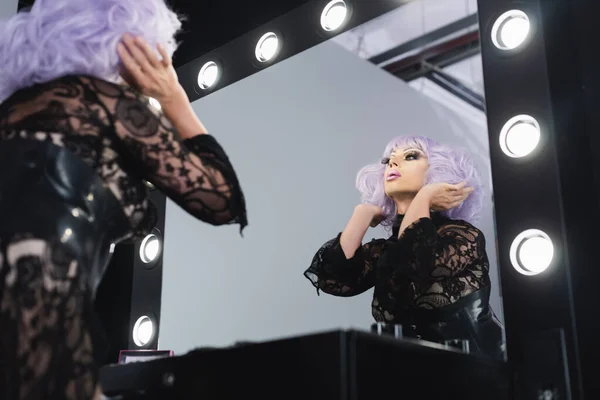 迷人的低视角拖曳女王在镜子附近调整紫色假发 — 图库照片