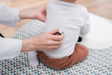 Aile doktorunun klinikteki tıbbi kanepede bebeğinin arkasını incelemesi. 
