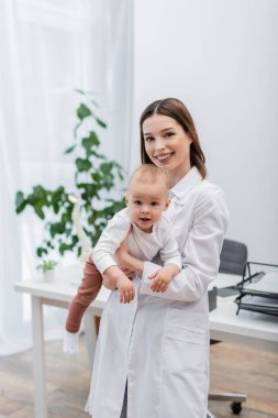 Neşeli aile doktoru bebeği hastanede tutuyor. 