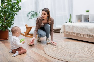 Bebek elinde elma tutuyordu. Gülümseyen anne ve oyuncak arabanın yanında. 