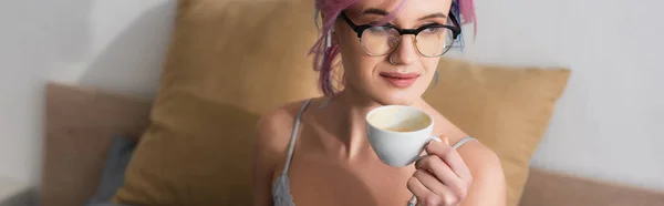 戴着眼镜和耳机的年轻女子举着一杯咖啡 一面横幅 — 图库照片