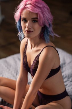 Siyah seksi iç çamaşırlı genç bir kadın resmi. Kameraya bakıyor.