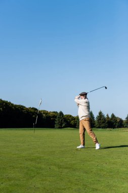 Düz şapkalı son sınıf öğrencisi golf oynuyor. 