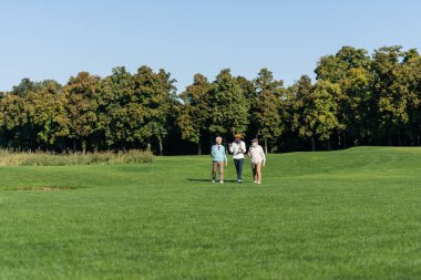 Golf sopalarıyla sahada yürüyen ırklar arası kıdemli adamlar.