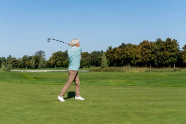 Asyalı son sınıf öğrencisi yeşil çimlerde golf oynuyor. 