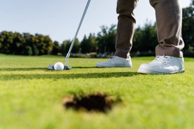 Beyaz spor ayakkabılı bir adamın çimenlikte golf oynaması kısmi bir bakış açısı