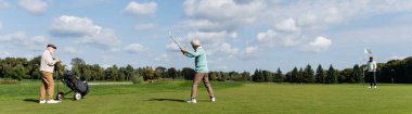 Kıdemli Asyalı arkadaş golf oynuyor. Bayrak sopası, golf arabası, pankart.