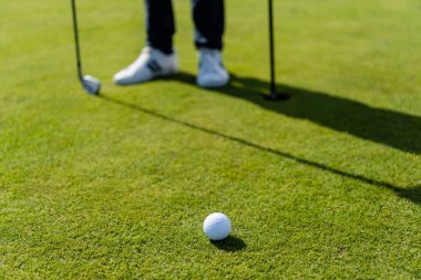 Bulanık adamın yanındaki yeşil çimenlikte golf topu 