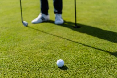 golf ball on green lawn near blurred man  clipart