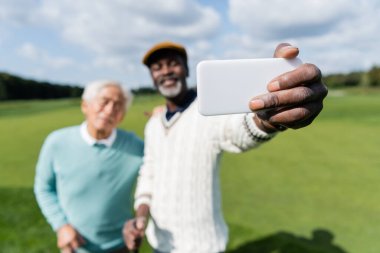 Bulanık Afrikalı Amerikalı bir adam Asyalı bir arkadaşla selfie çekiyor. 