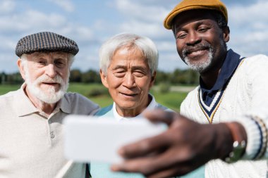Neşeli Afrikalı Amerikalı adam, çok ırklı üst düzey arkadaşlarıyla selfie çekiyor.  