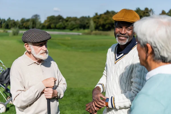 Seniores Multiétnicos Homens Segurando Tacos Golfe Falando Com Desfocado Asiático — Fotografia de Stock