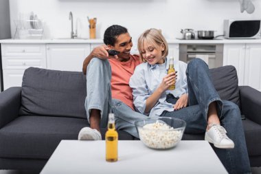 Mutlu Afrikalı Amerikalı adam elinde bira şişesi olan neşeli kadına bakıyor. 