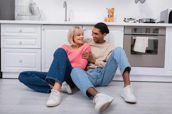 Cheerful Multiethnic Couple Sitting Floor Modern Kitchen — Fotografia de Stock