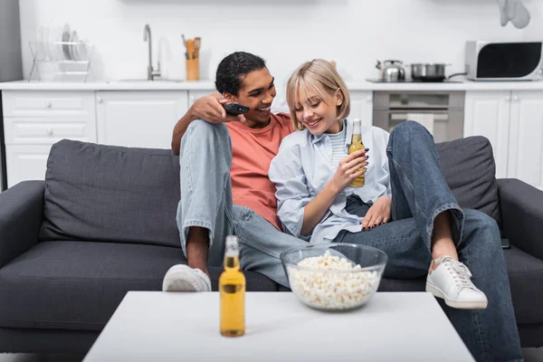Mutlu Afrikalı Amerikalı adam elinde bira şişesi olan neşeli kadına bakıyor. 