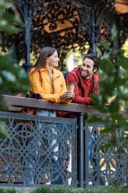 Parmaklıklarda dürbünün yanında kağıt bardak tutan pozitif gezgin ve erkek arkadaşı dışarıda. 