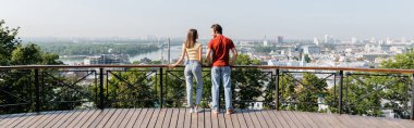 Side view of positive travelers standing near railing on viewpoint in city, banner  clipart