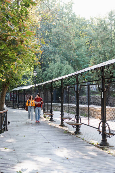 Travelers with coffee, binoculars and map walking on urban street 