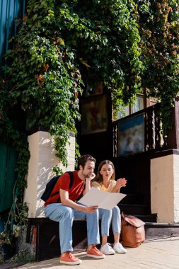 Dışarıdaki haritaya bakan sırt çantalı gezginler. 