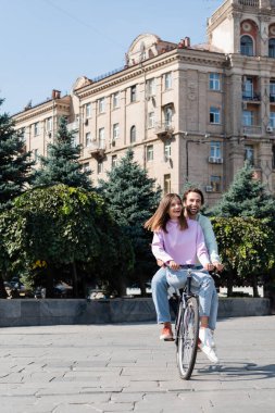 Şehir caddesinde bisiklet süren neşeli genç çift 