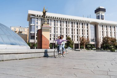 KYIV, UKRAINE - 1 Eylül 2021: Gülümseyen kadın erkek arkadaşıyla birlikte şehir caddesinde, Independence Meydanı 'nda safraya biniyor