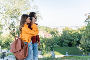 Sırt çantalı turistin erkek arkadaşının yanında dürbünle baktığı yan manzara.